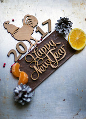 Wooden inscription Happy New Year and a rooster is on top of the