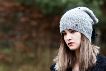 Thoughtful young woman in woolen grey cap