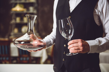 Man taking vase with wine and goblet