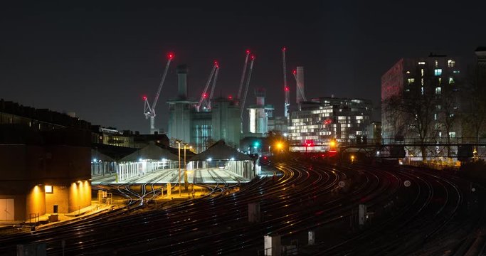 Time lapse clip of trains traveling in London at night. Cranes and construction site in the background.