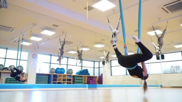 Slow motion, girl hanging upside down on a hammock to fly yoga and does twine