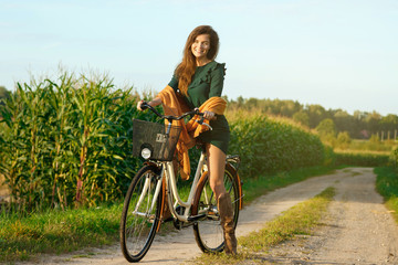 Fototapeta na wymiar Woman is cycling by the country road in the cornfield