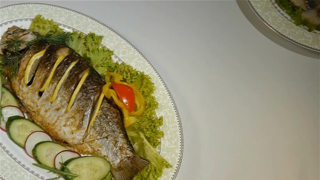 Baked carp with spices and lemon on white pan top view