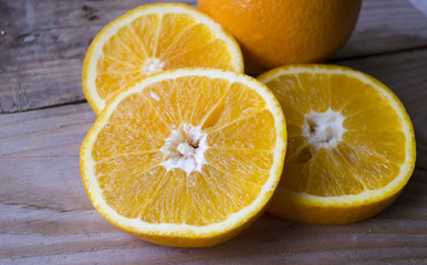 Fototapeta na wymiar Fresh oranges sliced on wooden table. Still life of ripe fruit. Sliced juicy citrus fruits. Orange background. Close-up of orange fruit