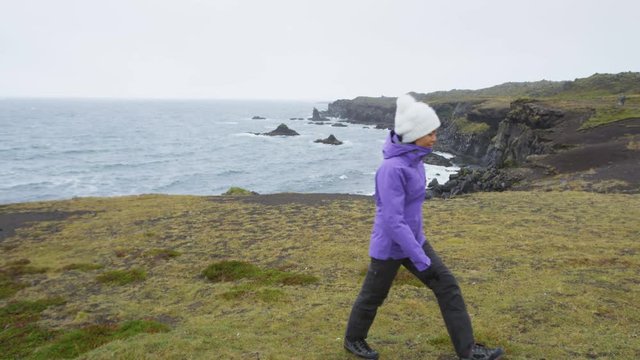 Iceland tourist on travel walking and hiking on Arnarstapi Snaefellsnes enjoying view of dramatic coast and ocean. Happy woman sightseeing visiting Arnarstapi, Snaefellsnes, West Iceland.