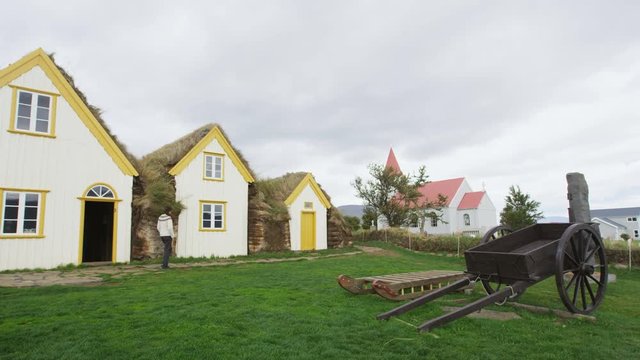 Old Farmhouse Laufas Glaumbaer farm Folk Museum turf roof houses in Varmahlid, Skagafjordur, Iceland, Europe. Icelandic tourist destination and attraction landmark. Woman walking in Icelandic sweater.