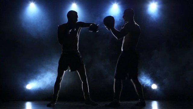 Coach helps the boxer to fulfill kick. Slow motion