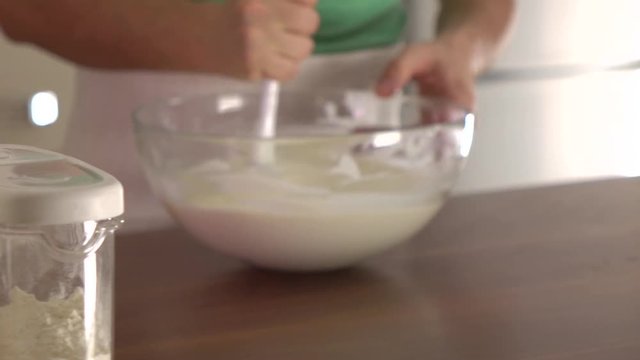 Man stirring dough in a glass bowl. Steadicam slow motion shot