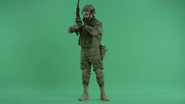 Soldier standing and targeting around at green screen