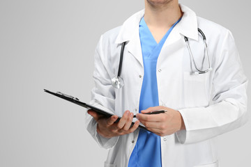 Doctor with clipboard on light background, closeup