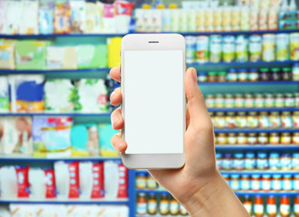 Woman with smartphone in store, closeup. Blank screen.