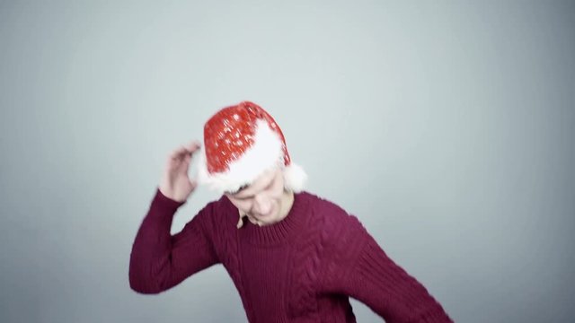 Young man in santa hat running and smiling at studio gray background
