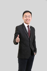 Handsome Asian man showing thumb up sign, on light background