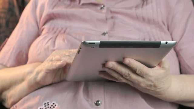 Elderly woman with the silver digital tablet computer indoors. Close up