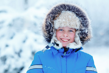 Cute little boy wearing warm clothes playing on winter forest