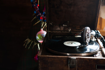 Image of Christmas. Gramophone playing a record. Gramophone with a vinyl record on a background of Christmas decorations, cap, Christmas tree and bright lights.