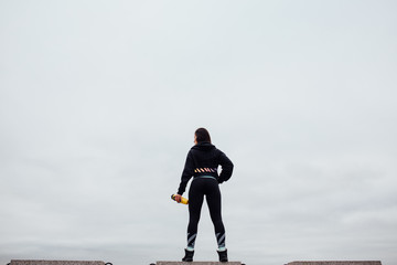 Back view of athlete with the bottle, drinking after exercising.