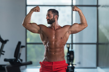 Fototapeta na wymiar Bodybuilder Flexing Front Double Biceps Pose In Gym
