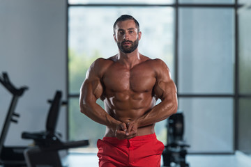 Obraz na płótnie Canvas Muscular Man Flexing Muscles In Gym
