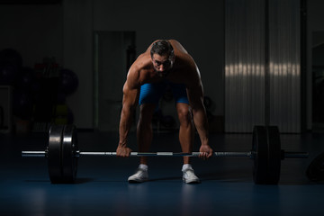 Fototapeta na wymiar Man In The Gym Exercising Back With Barbell