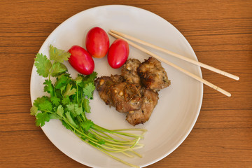 Tasty roasted pork with fresh vegetable and chopsticks in white plate on wood table