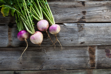 imperfect organic turnips, fresh green tops on authentic wood background