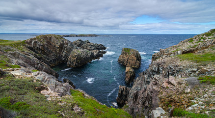Fototapeta na wymiar Cape Bonavista featuring coastal slabs of stone boulders and rocks that show their layers of formation over millions of years. Rocky boulder shoreline in Newfoundland, Canada.