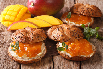 Sweet freshly baked rolls with mango jam, butter and mint close-up. horizontal