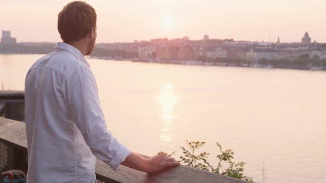 Man looking at sunset enjoying view. Young man relaxing enjoying calm serene moment in solitude in Stockholm  Sweden.