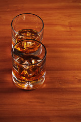 Highball whiskey glass with ice on wooden background. Closeup.