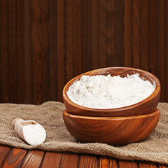 Fototapeta na wymiar Flour in wooden bowl on nature background. Closeup.