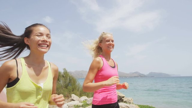 Exercise running women jogging happy by beach training healthy lifestyle. Two fit female runners talking happy and smiling in workout. Multiracial Asian and Caucasian woman. RED EPIC  REAL TIME.