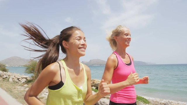 Running women runners training outdoors. Close up portrait of happy woman runner jogging outside with friends on beach. RED EPIC footage in SLOW MOTION.