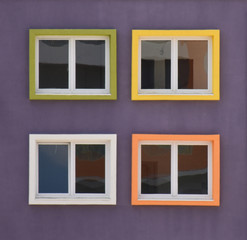 Fototapeta na wymiar Four colourful windows on a building facade