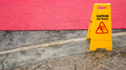 Yellow Wet Floor in rain season with red carpet