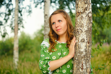 Portrait of the girl leaned against the trunk of a birch on natural background