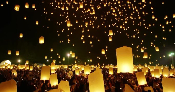 Thousands of sky lanterns floating into night sky at religious festival in Thailand