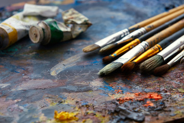 Oil paints and paint brushes on a palette.