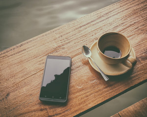 Smart phone and blank coffee mug with coffee stains stuck , after drinking it on the wooden table