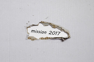 The word mission 2017 appearing behind torn paper