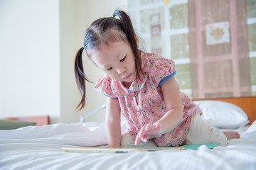 Little asian girl playing game on tablet computer