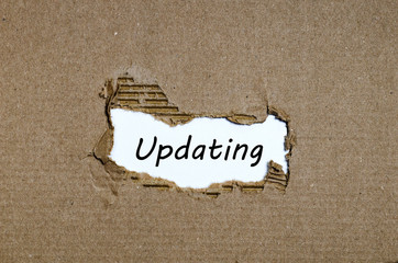 The word updating appearing behind torn paper