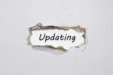 The word updating appearing behind torn paper