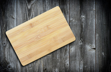 Naklejka na ściany i meble Empty bamboo cutting board on a old wooden table for product display.Top view