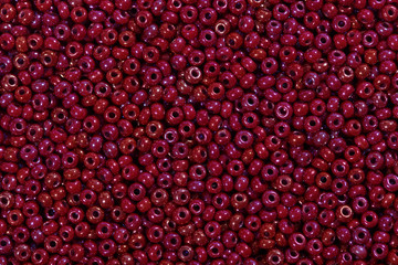 Seed beads of dark red color on the textile background.
