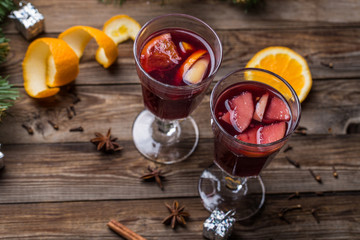 Two glasses of hot mulled wine with oranges, apples and spices