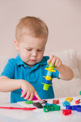 Child with colorful clay. Toddler playing and creating toys from play dough. Boy molding modeling clay.