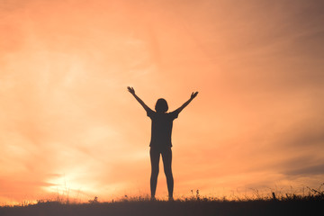Young woman with raised hands standing on sunset
