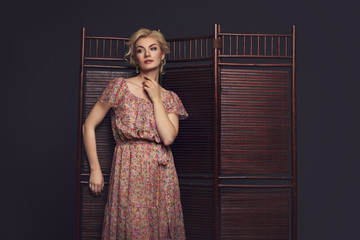 Beautiful girl standing near folding screen 