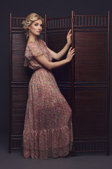 Beautiful girl standing near folding screen 